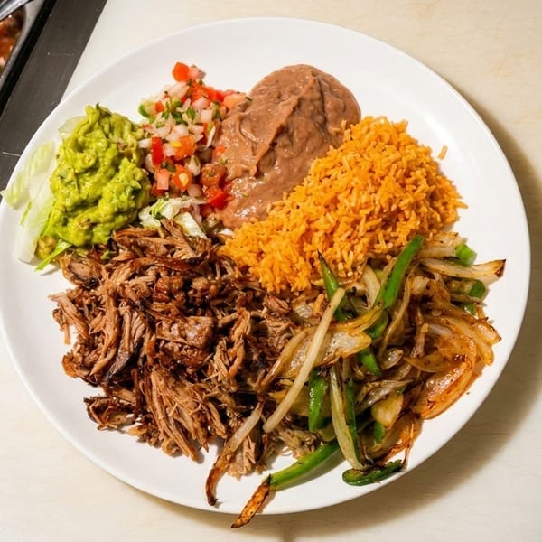 A plate of Mexican food with shredded pork, rice, beans, guacamole, pico de gallo, and fajita vegetables.